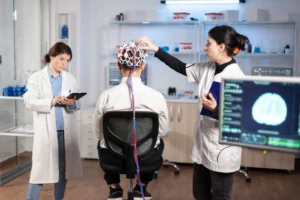 back view man patient wearing performant brainwave scanning headset sitting neurological research laboratory while medical researcher adjusting it examining nervous system typing tablet
